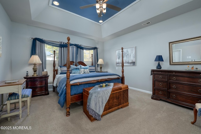 bedroom featuring light carpet, baseboards, visible vents, and a tray ceiling