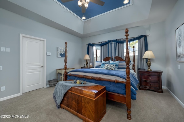 bedroom with ceiling fan, carpet floors, a tray ceiling, and baseboards