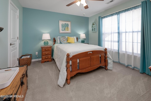 bedroom with light carpet, a ceiling fan, visible vents, and baseboards