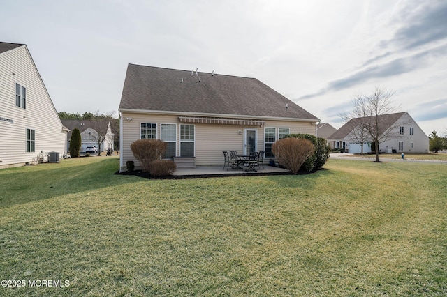 rear view of house featuring central air condition unit, a patio area, a shingled roof, and a lawn