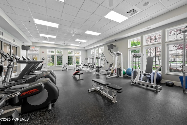 exercise room with a paneled ceiling, visible vents, and baseboards