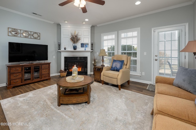 living room with a large fireplace, visible vents, crown molding, and wood finished floors