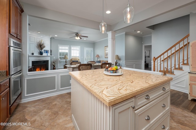 kitchen with open floor plan, decorative light fixtures, stainless steel double oven, a fireplace, and a decorative wall