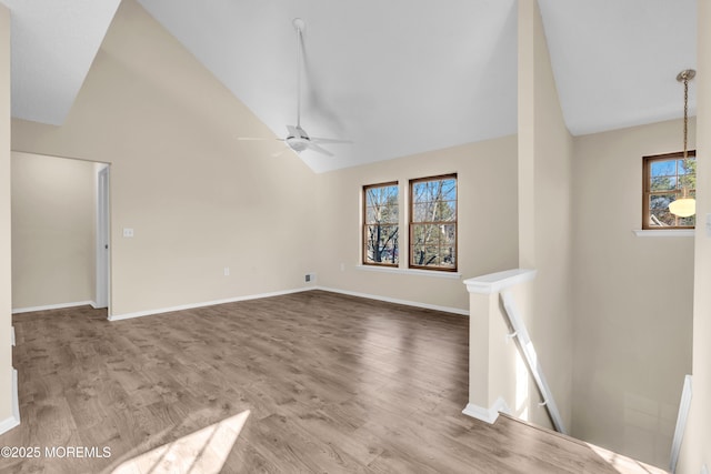 unfurnished living room featuring ceiling fan, high vaulted ceiling, wood finished floors, and baseboards