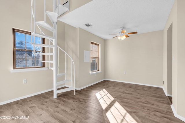 interior space featuring ceiling fan, wood finished floors, visible vents, and baseboards