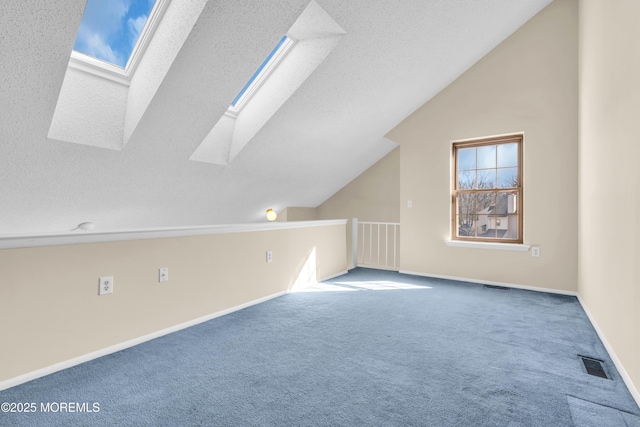 bonus room featuring a textured ceiling, vaulted ceiling with skylight, visible vents, baseboards, and carpet