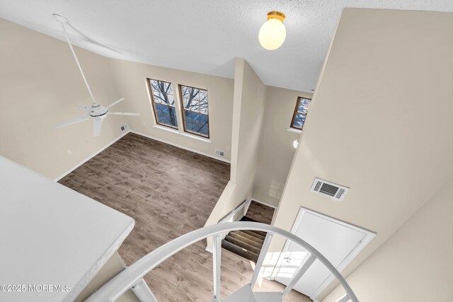 staircase with visible vents, ceiling fan, a textured ceiling, wood finished floors, and baseboards