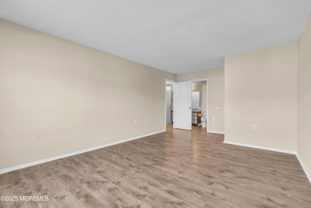 unfurnished room featuring light wood-style floors, baseboards, and a textured ceiling