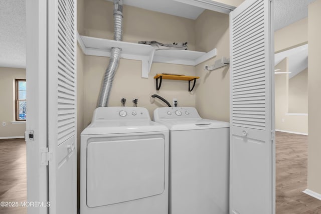 laundry room featuring a textured ceiling, laundry area, wood finished floors, baseboards, and independent washer and dryer