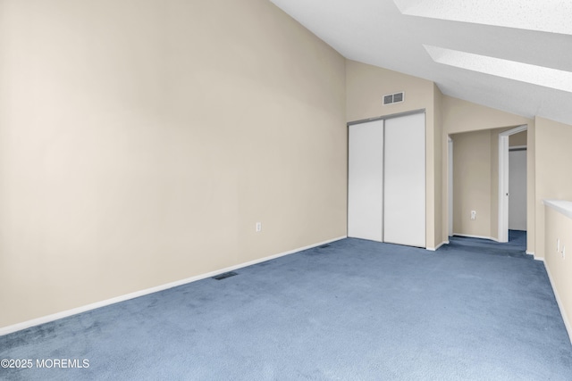 unfurnished bedroom featuring carpet floors, vaulted ceiling with skylight, visible vents, and a closet