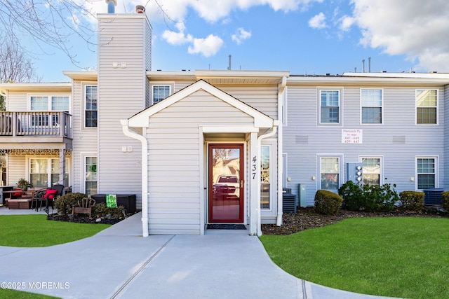 multi unit property featuring a front lawn, a chimney, and cooling unit