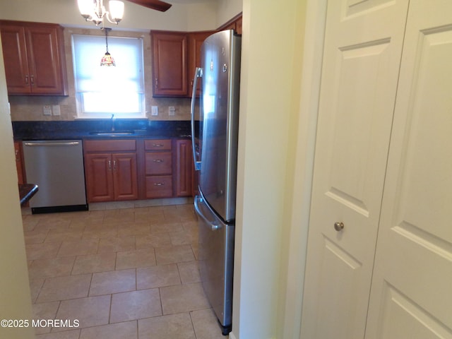 kitchen featuring dark countertops, appliances with stainless steel finishes, decorative backsplash, and a sink