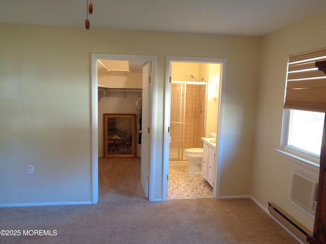 unfurnished bedroom with baseboards, a walk in closet, carpet floors, a baseboard heating unit, and a closet