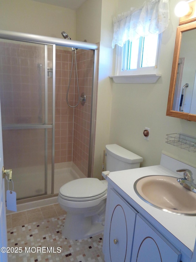 bathroom featuring toilet, a shower stall, vanity, and tile patterned floors