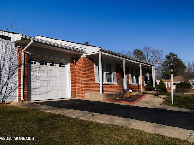 view of front of house featuring brick siding, an attached garage, and aphalt driveway