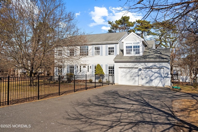 colonial house with aphalt driveway, fence, and a garage