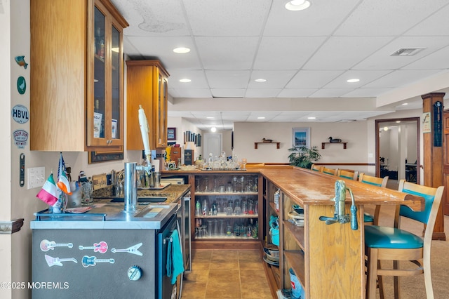 interior space with visible vents, wet bar, recessed lighting, a drop ceiling, and tile patterned floors