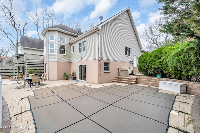 rear view of property with outdoor dining space, stairway, a patio area, and stucco siding