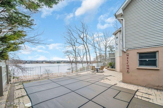 view of patio featuring stairs, fence, and a water view