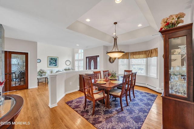 dining room with a tray ceiling, recessed lighting, light wood-type flooring, and a baseboard radiator