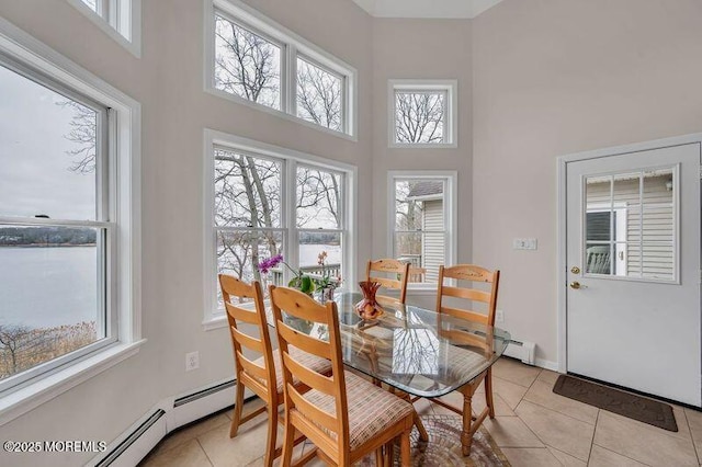 dining space featuring light tile patterned floors, baseboards, baseboard heating, and a towering ceiling