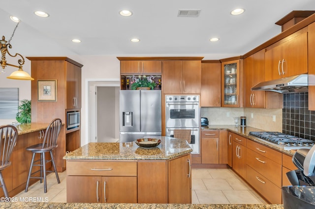 kitchen with visible vents, under cabinet range hood, light stone counters, light tile patterned floors, and appliances with stainless steel finishes