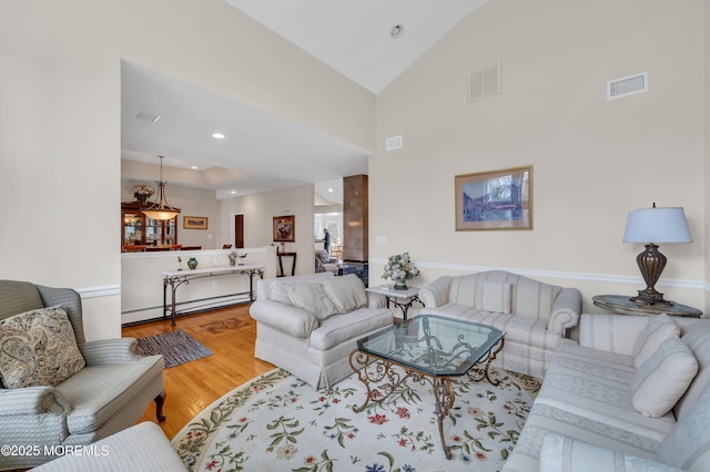 living area featuring a baseboard heating unit, vaulted ceiling, wood finished floors, and visible vents