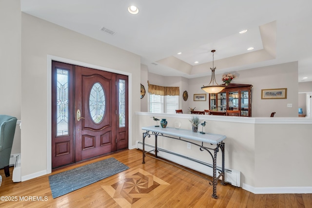 entrance foyer with visible vents, a tray ceiling, baseboard heating, recessed lighting, and wood finished floors