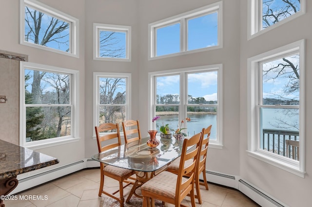 dining space featuring light tile patterned floors, a wealth of natural light, and a baseboard radiator