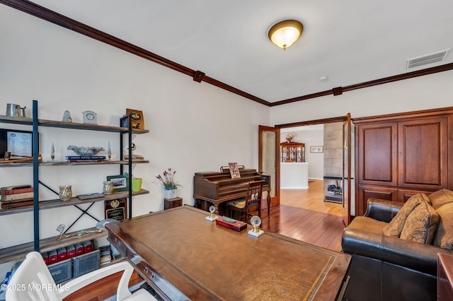 office space with hardwood / wood-style floors, crown molding, and visible vents