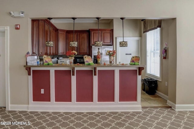 kitchen with freestanding refrigerator, pendant lighting, a peninsula, and baseboards