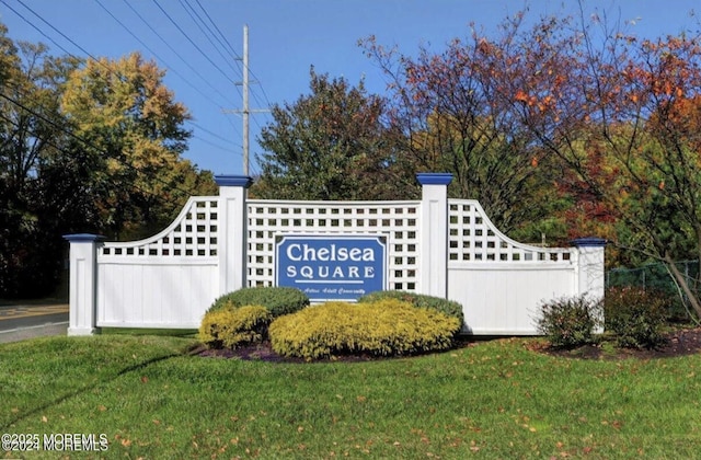 community / neighborhood sign with a yard and fence