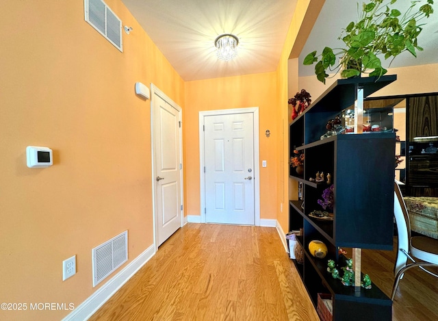 foyer entrance featuring visible vents, baseboards, and wood finished floors