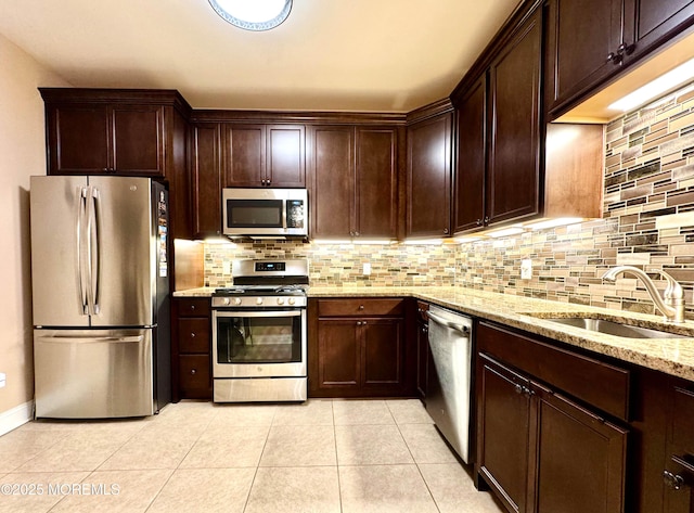 kitchen featuring tasteful backsplash, appliances with stainless steel finishes, light stone counters, a sink, and light tile patterned flooring