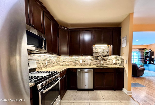 kitchen with light stone countertops, appliances with stainless steel finishes, decorative backsplash, and dark brown cabinets