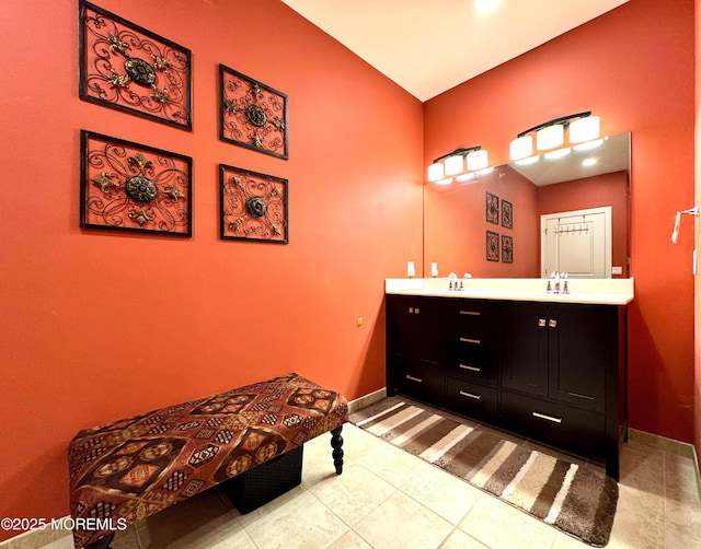 bathroom featuring double vanity, tile patterned flooring, a sink, and baseboards