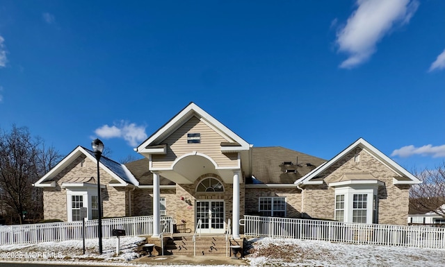 view of front of house with a porch, french doors, brick siding, and fence