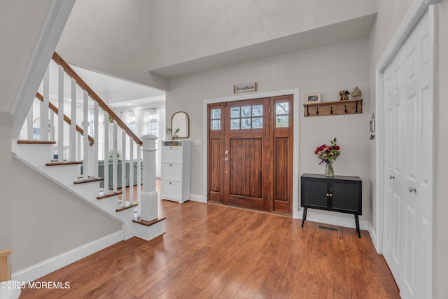 foyer featuring baseboards, plenty of natural light, stairway, and wood finished floors