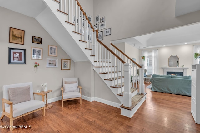 stairway with a lit fireplace, hardwood / wood-style floors, recessed lighting, and baseboards