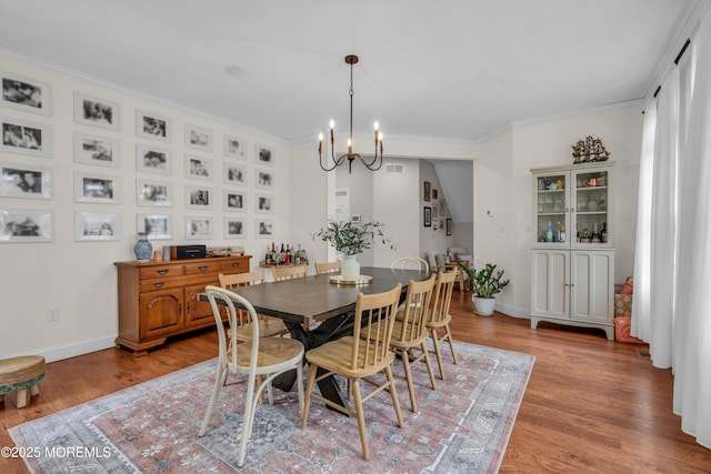 dining area with crown molding, an inviting chandelier, baseboards, and light wood-style floors