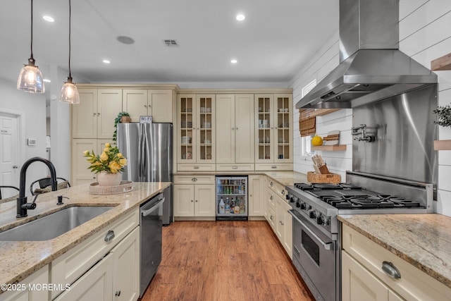 kitchen with beverage cooler, stainless steel appliances, a sink, exhaust hood, and cream cabinetry