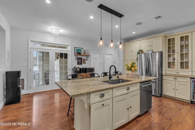 kitchen featuring french doors, cream cabinetry, a breakfast bar area, stainless steel appliances, and a sink