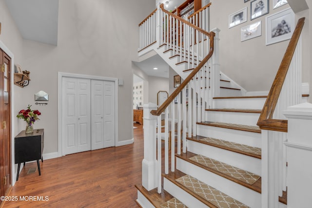 entrance foyer with a towering ceiling, stairway, baseboards, and wood finished floors