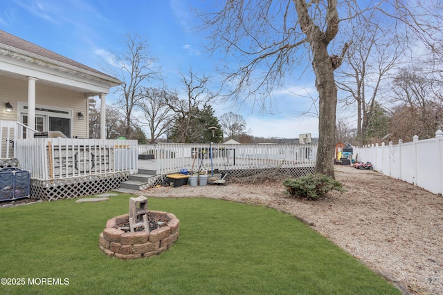 view of yard with a fire pit, a deck, and a fenced backyard