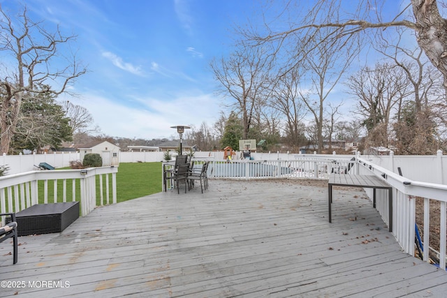 wooden deck featuring a fenced backyard, an outbuilding, and a yard