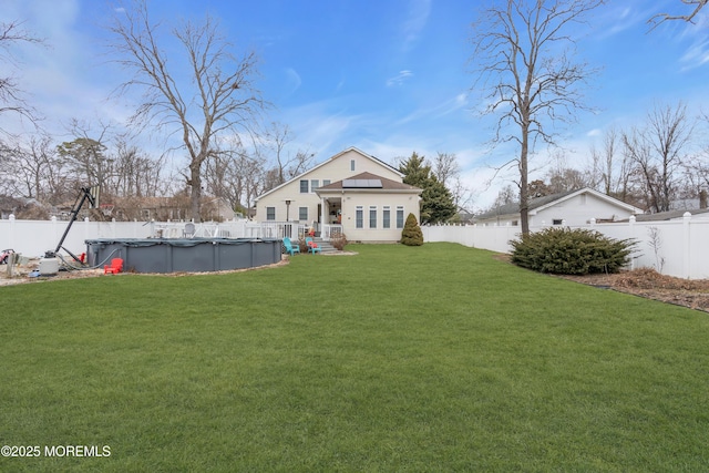 rear view of house with a lawn, a fenced backyard, and a fenced in pool