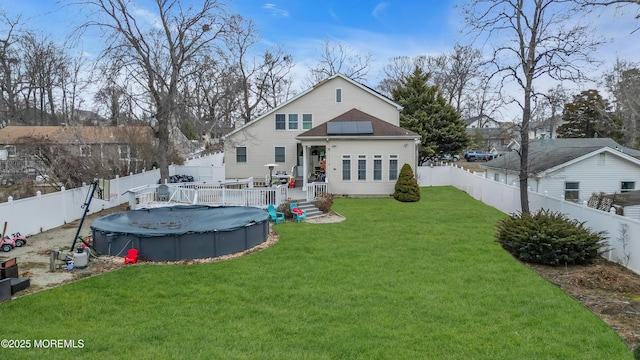 rear view of house featuring a fenced in pool, a yard, roof mounted solar panels, a deck, and a fenced backyard