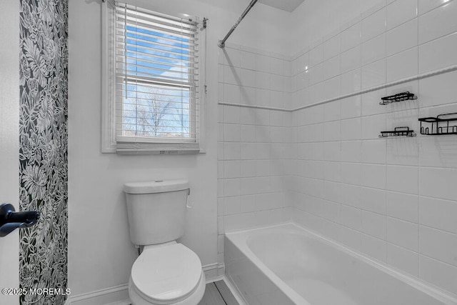 bathroom featuring toilet, washtub / shower combination, and baseboards