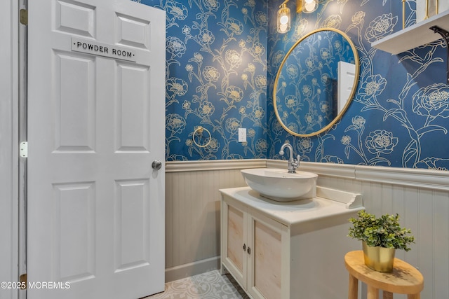 bathroom featuring wainscoting, vanity, and wallpapered walls