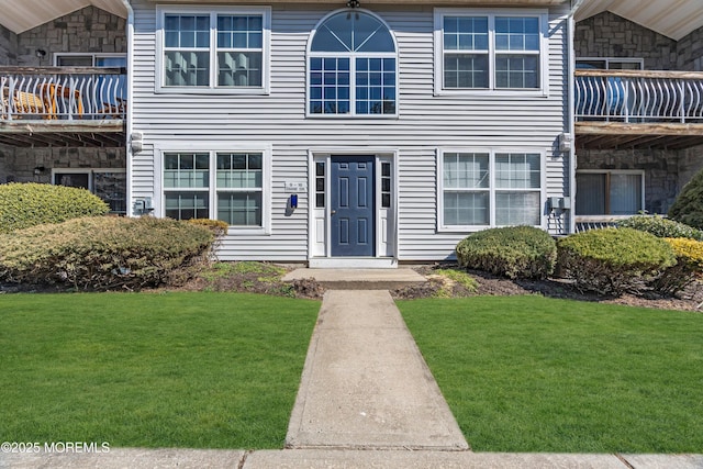 view of front of home featuring a balcony and a front lawn